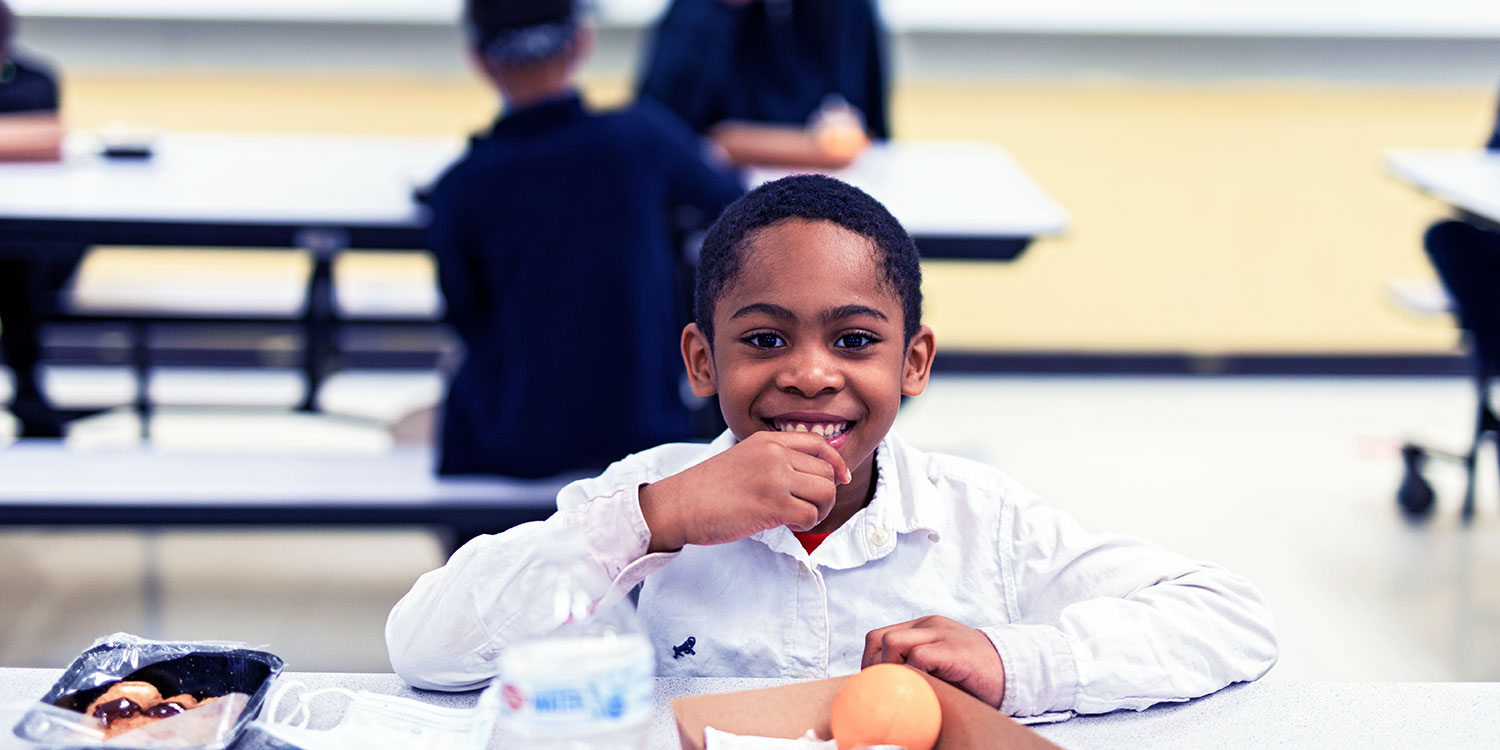 Smiling student eating lunch.