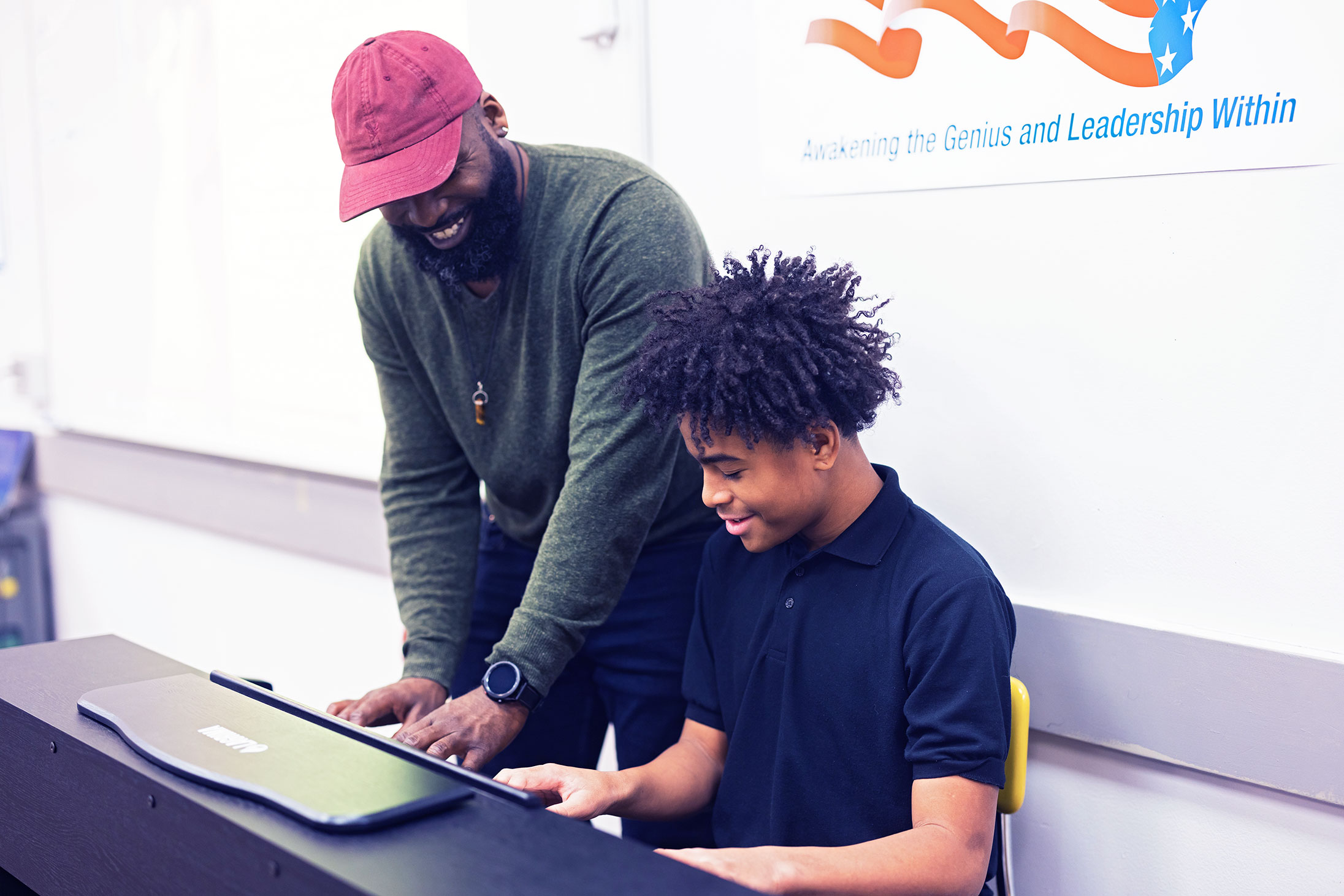 Teacher helping a student play on a keyboard.