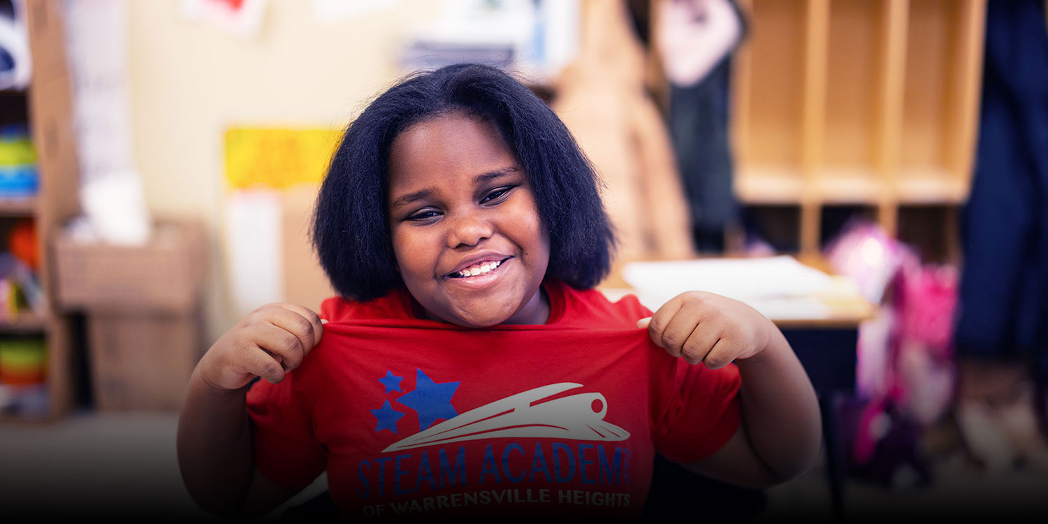 Smiling student showing off their STEAM Academy of Warrensville Heights shirt.